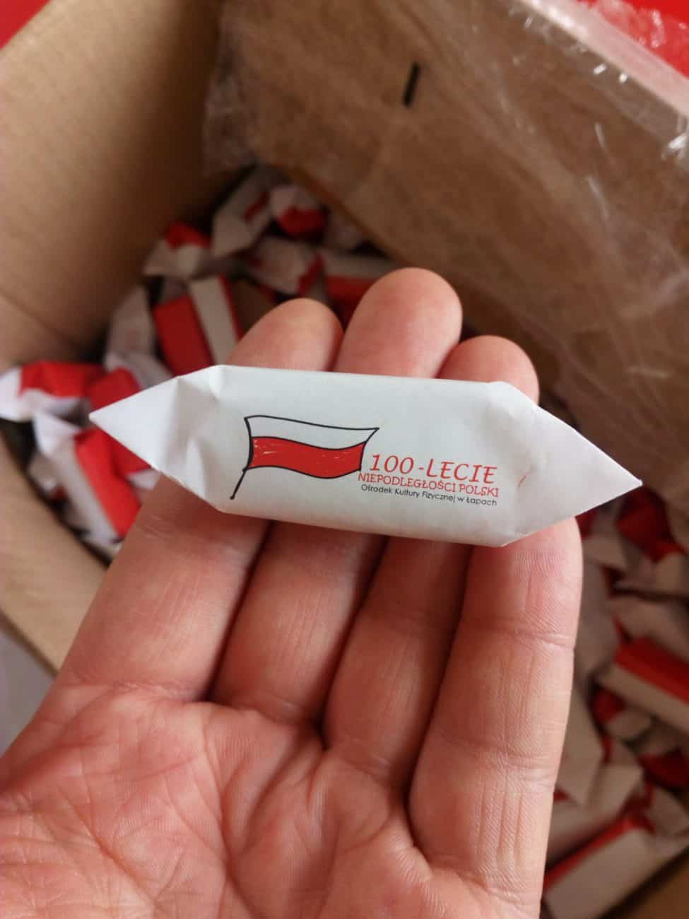 trzymane w ręku krówki reklamowe z logo 100-lecia niepodległości polski
