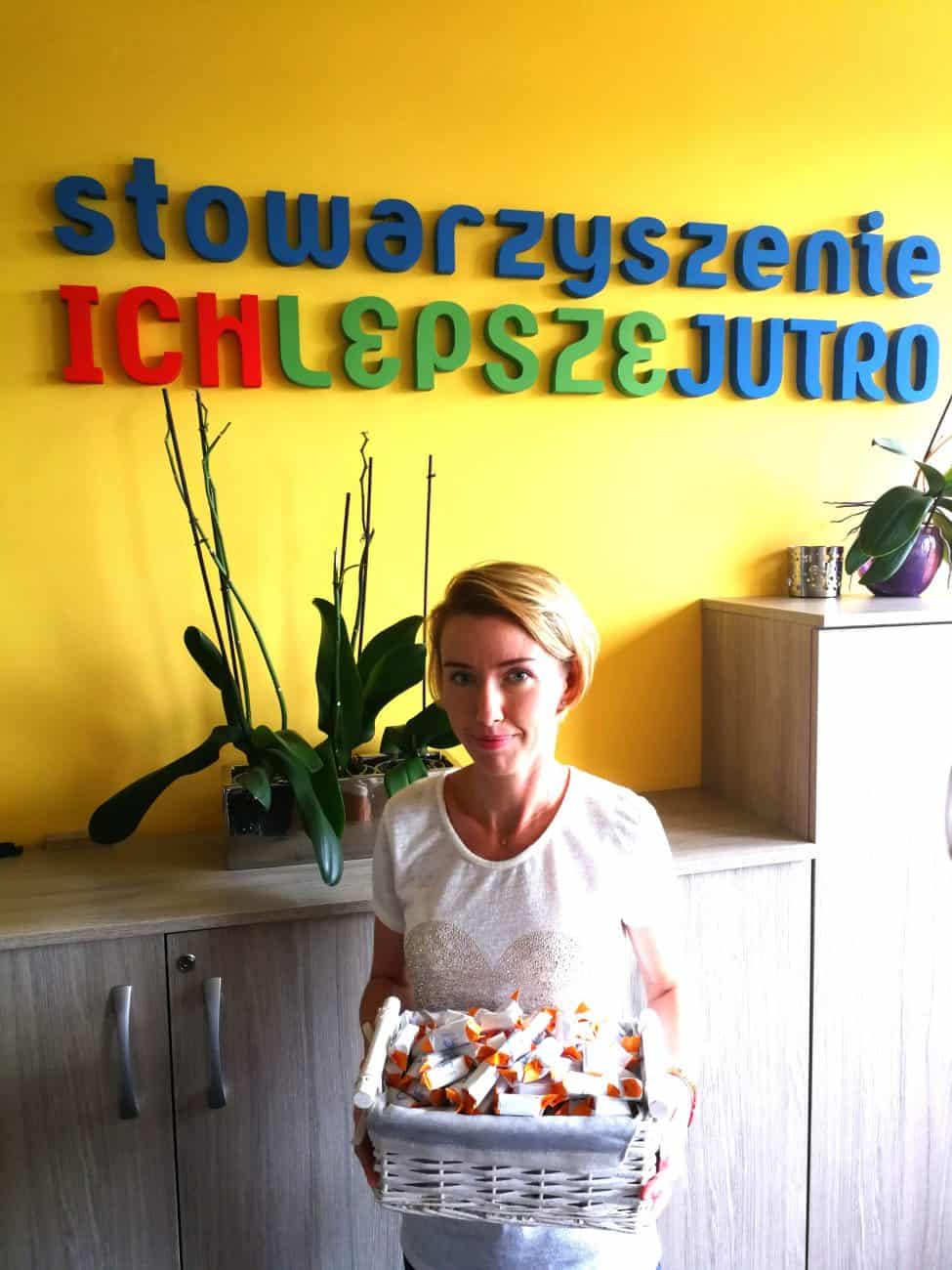 zdjęcie pani która trzyma krówki reklamowe z logo stowarzyszenia ich lepsze jutro